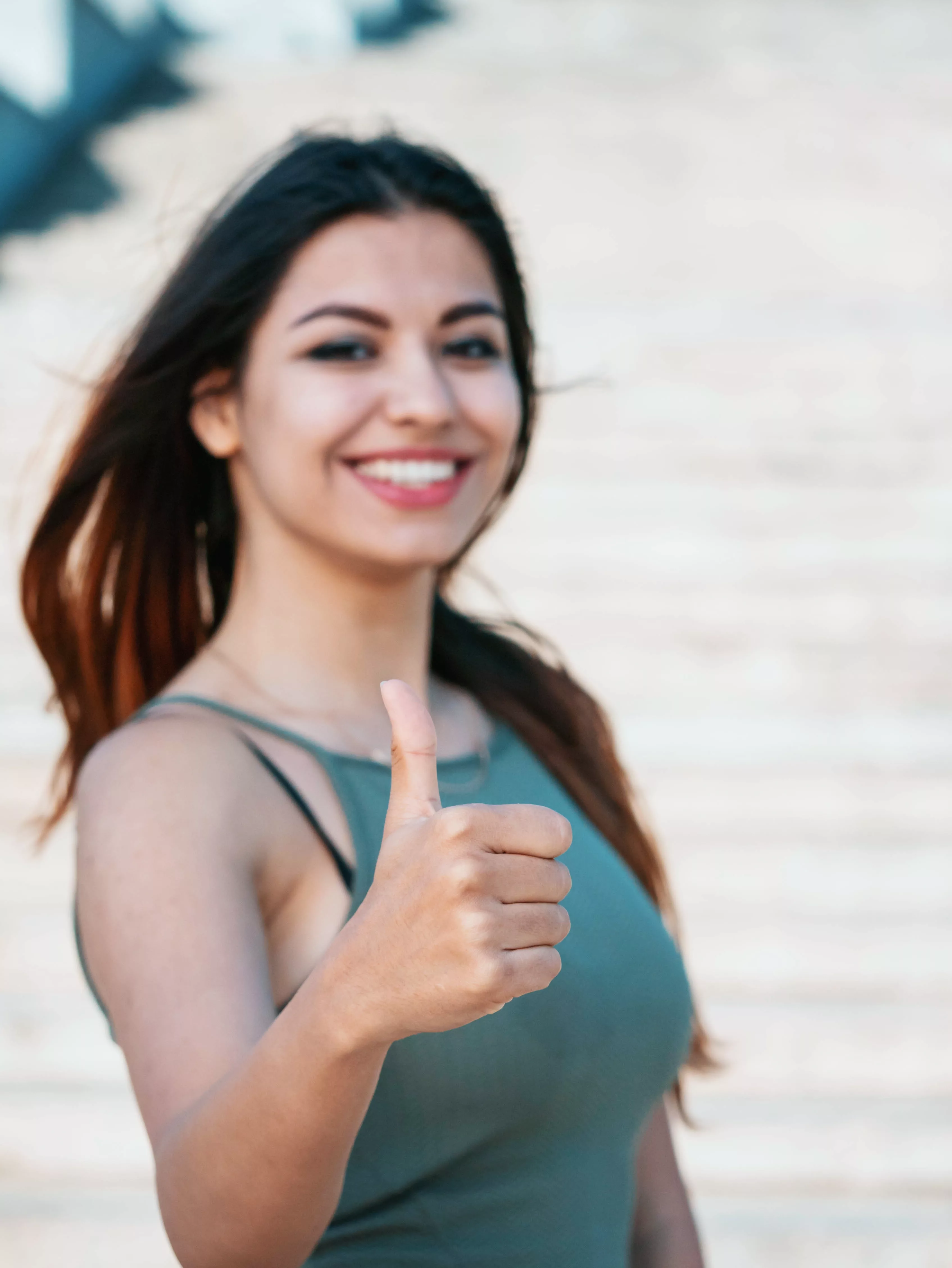 Portrait of young beautiful girl showing thumb up gesture and smiling outdoor